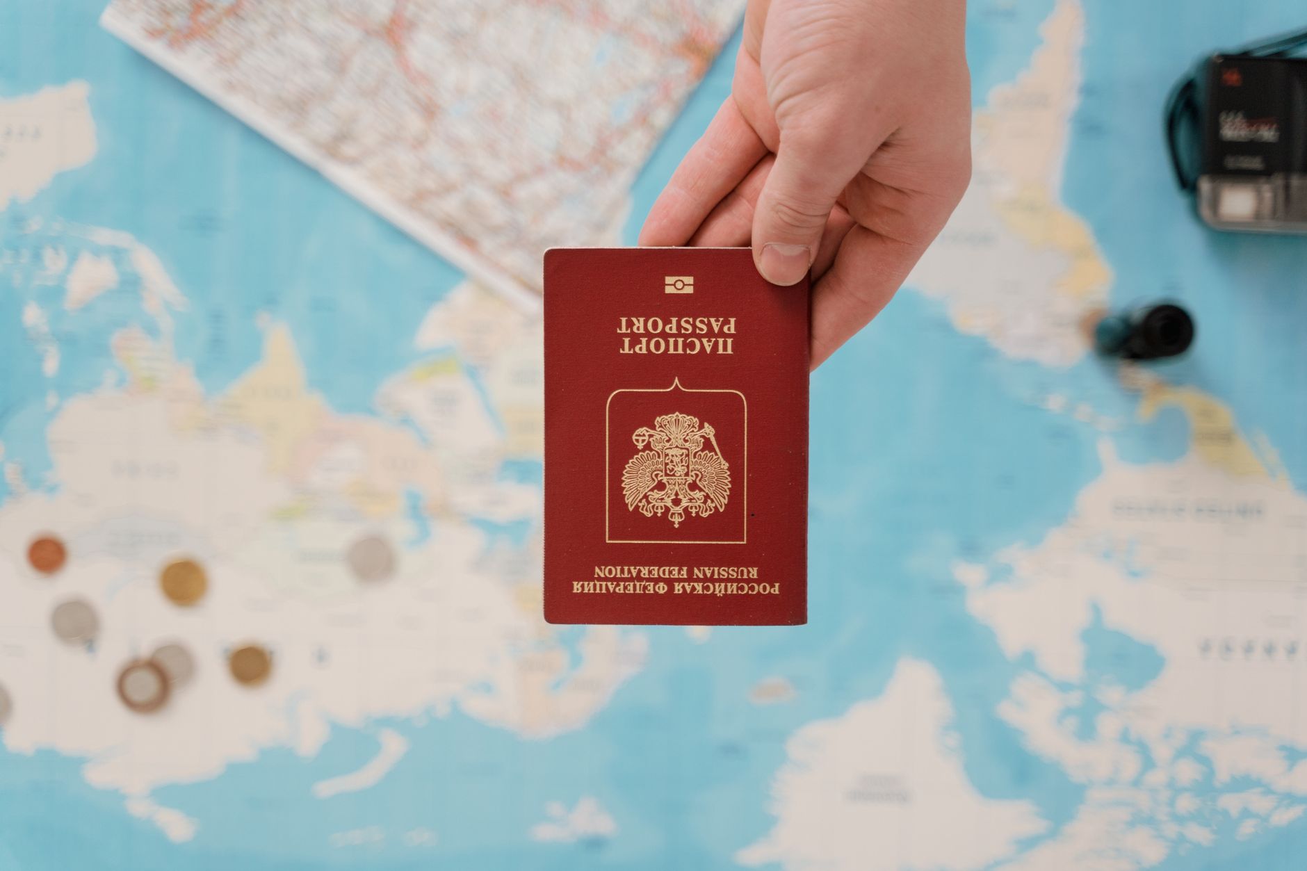 Une main tenant un passeport russe au-dessus d'une carte thématique de voyage, capturant des concepts de voyage dans le monde.
